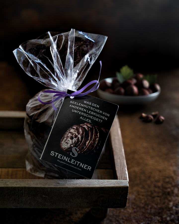 Schokolierte Piemonteser-Haselnuss-Lebkuchen „Seelenhutscher" von Steinleitner in transparenter Geschenktüte mit violettem Band
